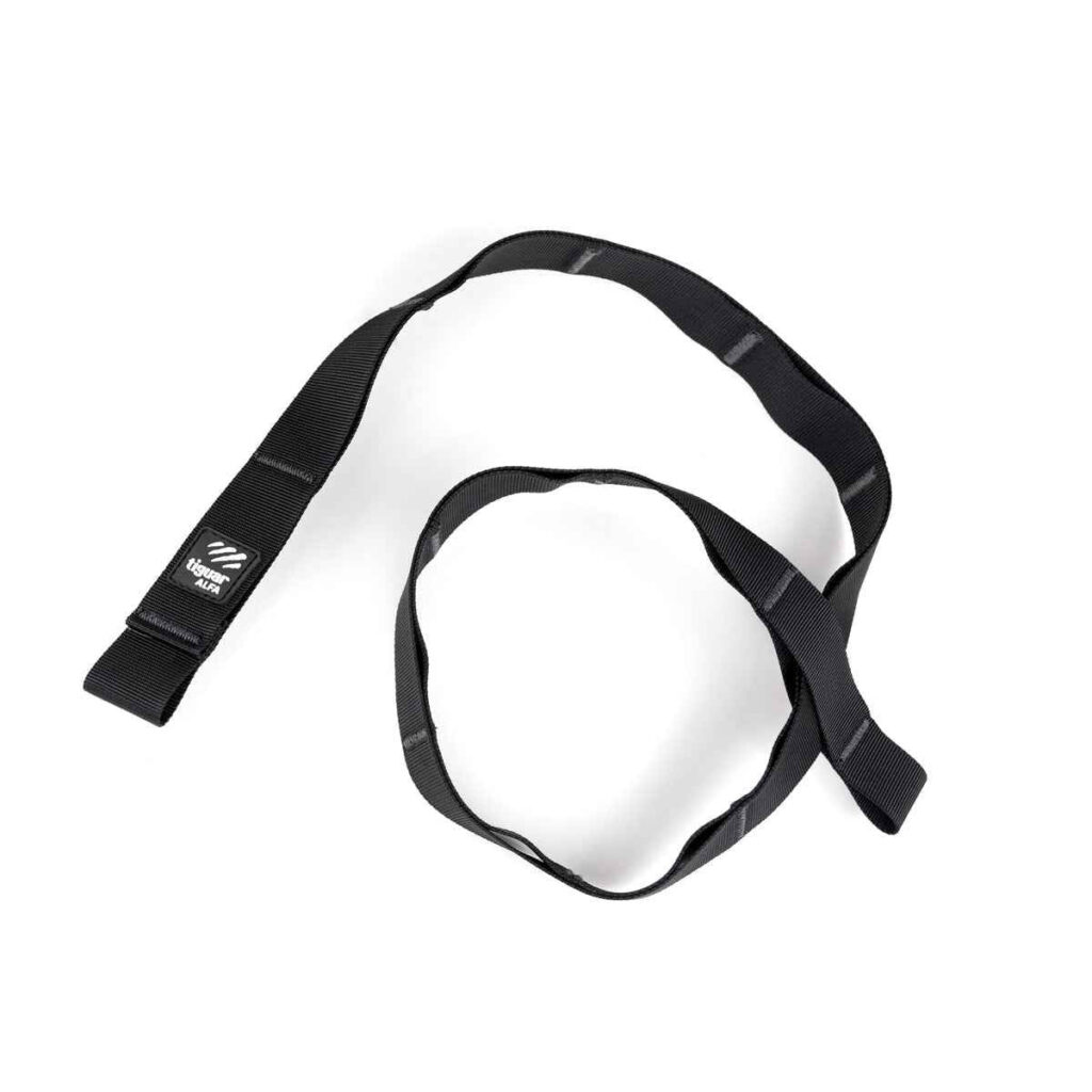 Ein schwarzes Nylonband mit aufgenähten Schlaufen, die sich in einem losen Kreis auf weißem Hintergrund aufrollen. An einem Ende des Bandes ist ein kleines schwarz-weißes Etikett mit einem Logo angenäht.