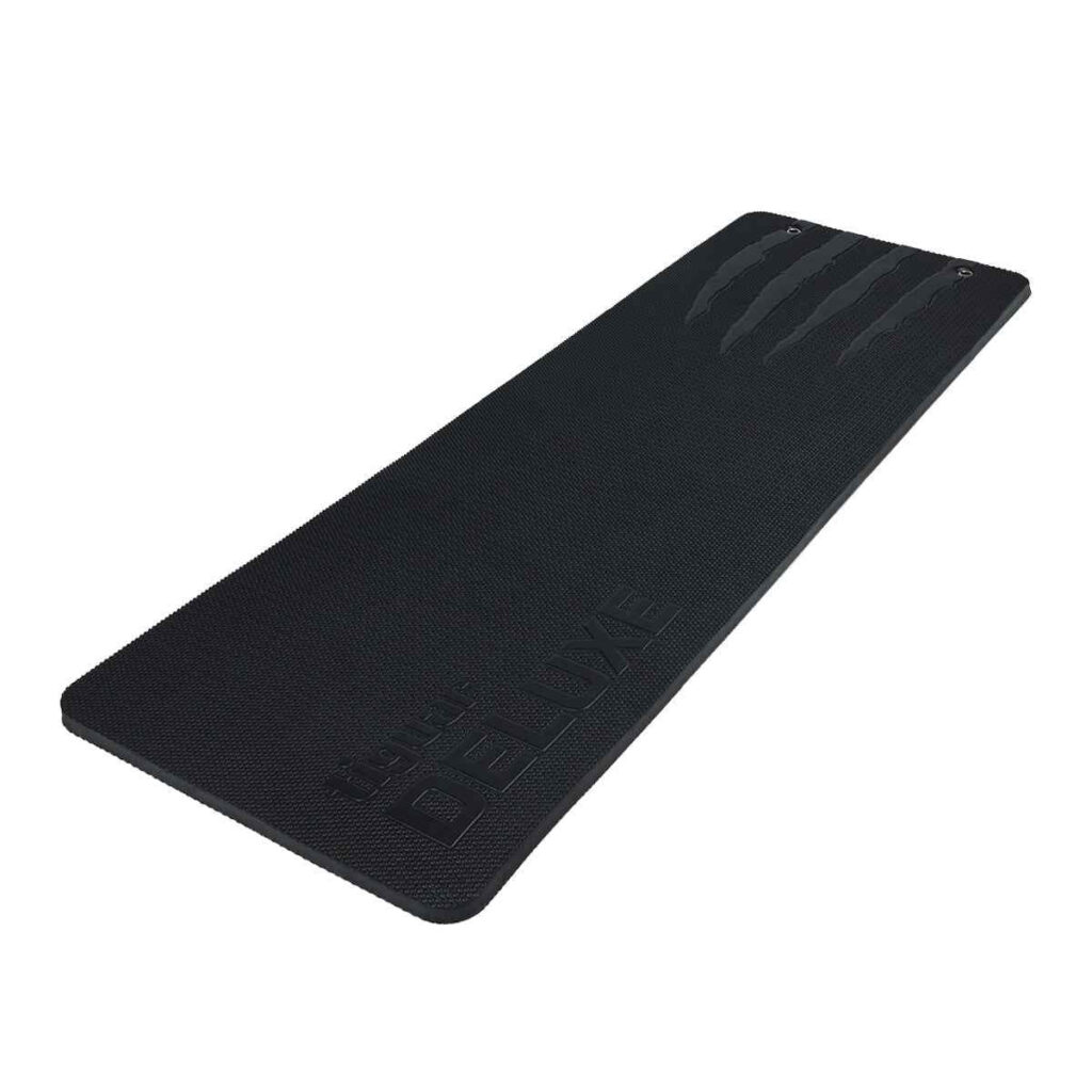Eine schwarze, rechteckige Übungsmatte mit leicht abgerundeten Ecken, strukturierter Oberfläche und dem Wort DELUXE, das an einem Ende eingeprägt ist. Die Matte hat drei kleine metallverstärkte Löcher am oberen Rand.