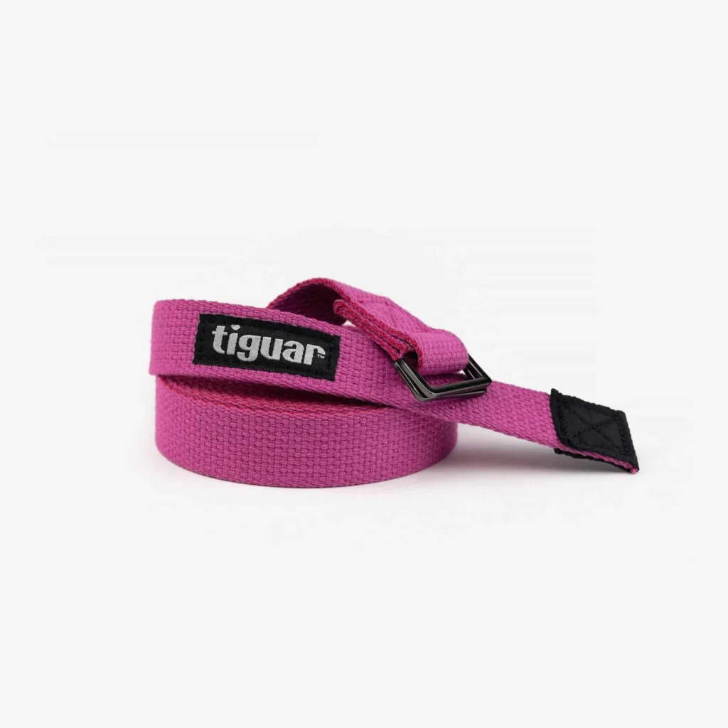 Ein aufgerollter Yogagurt aus rosa Stoff mit einer Metallschnalle und einem schwarzen Aufnäher mit der Aufschrift Tiguar auf weißem Hintergrund.
