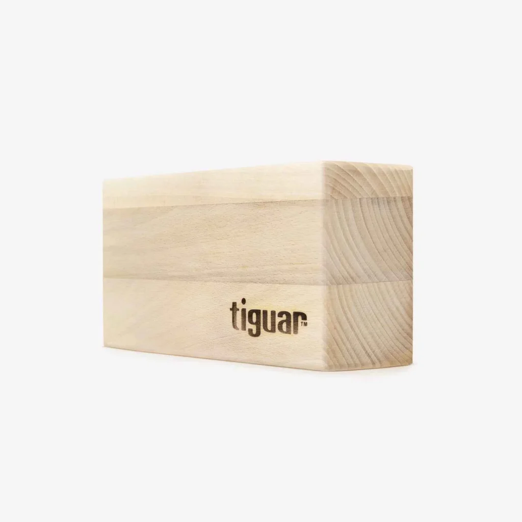 Ein heller Yogablock aus Holz mit abgerundeten Kanten und dem Aufdruck "Tiguar" auf einer Seite, der auf einem schlichten weißen Hintergrund steht.